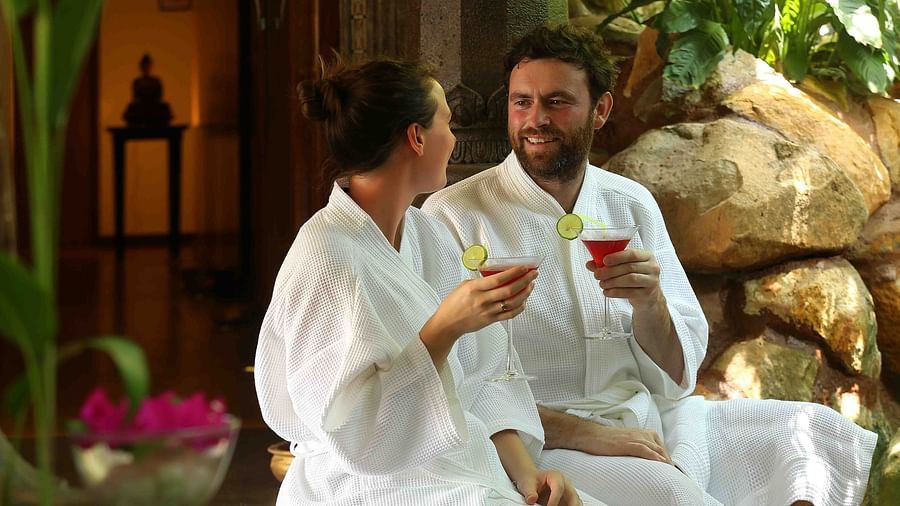 Two individuals in bathrobes holding a couple of glasses of cold beverages at Uday Samudra Leisure Beach Hotel
