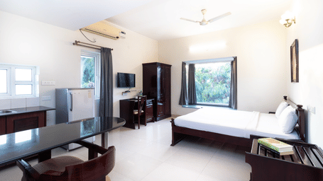 Hotel room with a double bed, an air conditioner, and grey curtains at Sanctum Suites Indiranagar, Bangalore.