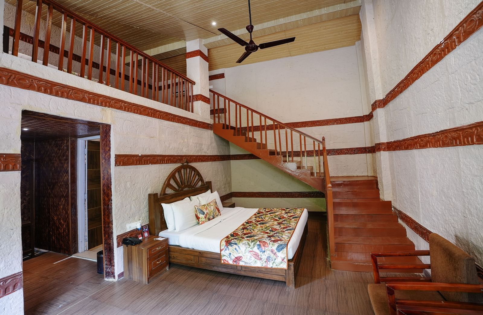 Duplex ethnic villa featuring a spacious bedroom and staircase leading to an additional room at Summit Green Lake Tea Resort & Spa, Kaziranga