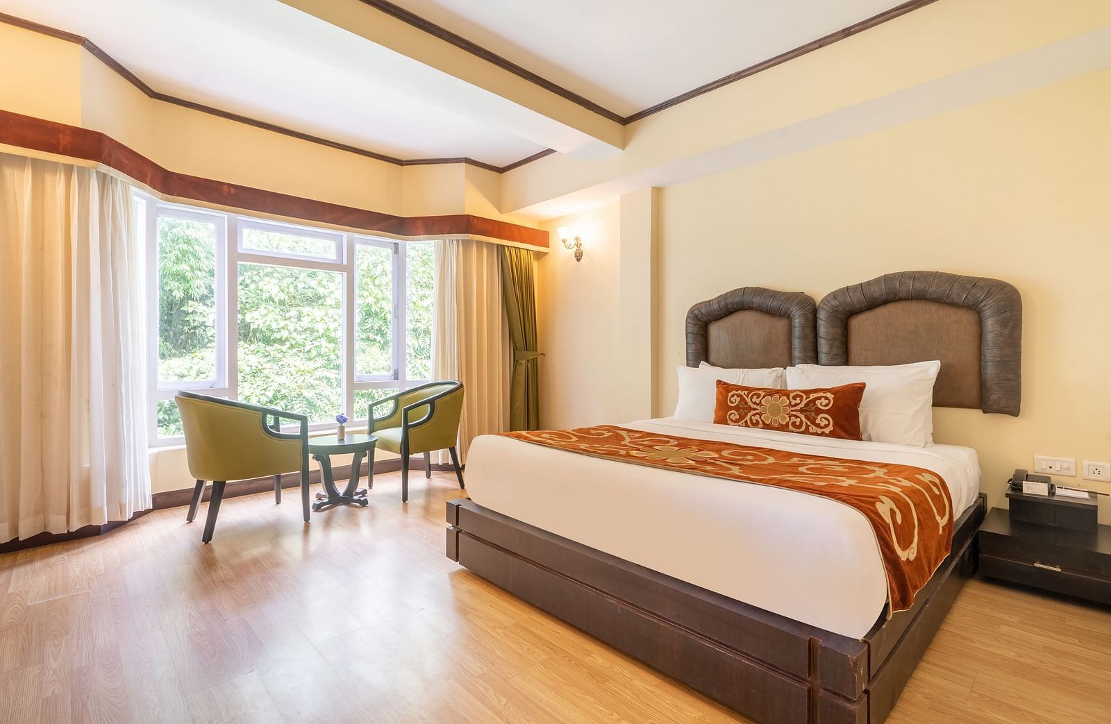 king size bed  with chairs near balcony of deluxe bed at Summit Lillium Hotel & Spa, Kalimpong