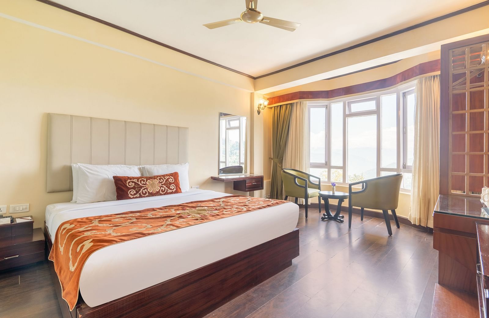 king size bed and chairs in the background near balcony of premium room at Summit Lillium Hotel & Spa, Kalimpong