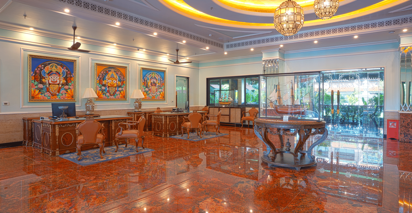 A wide view of the lobby lounge with seating area, decorative artwork, and a polished reddish marble floor at MAYFAIR Bay Resort, Paradeep.
