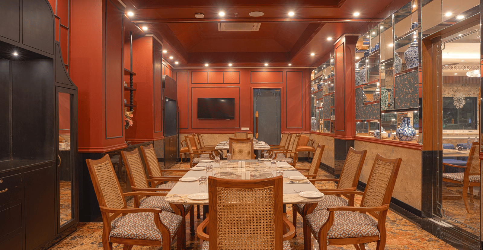 A dining room with a long wooden table set for a meal, surrounded by upholstered chairs and wood-panelled walls at MAYFAIR Bay Resort, Paradeep.