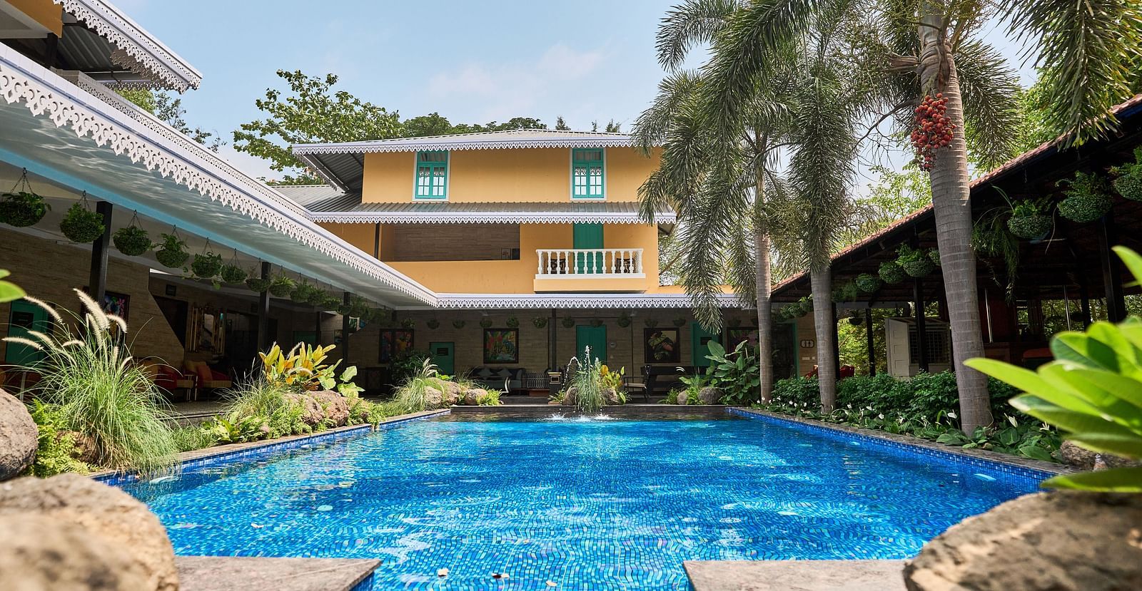 Swimming pool with a facade, surrounded by plants and trees at Mayfair Manor, Alibag