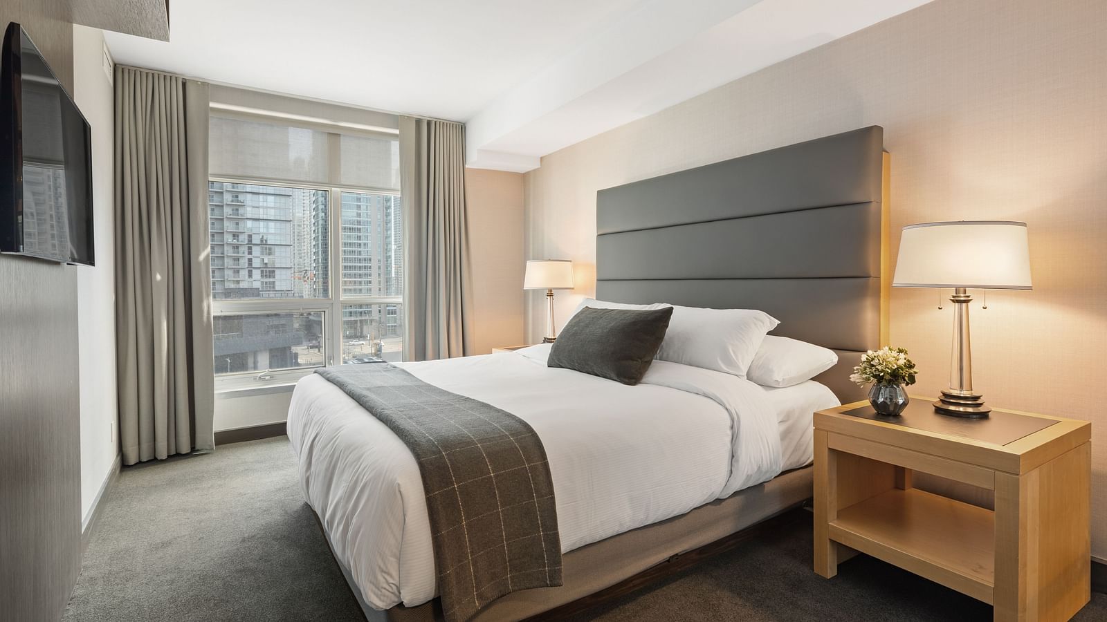 A double bed with cushioned headboard and a side table with a lamp on it