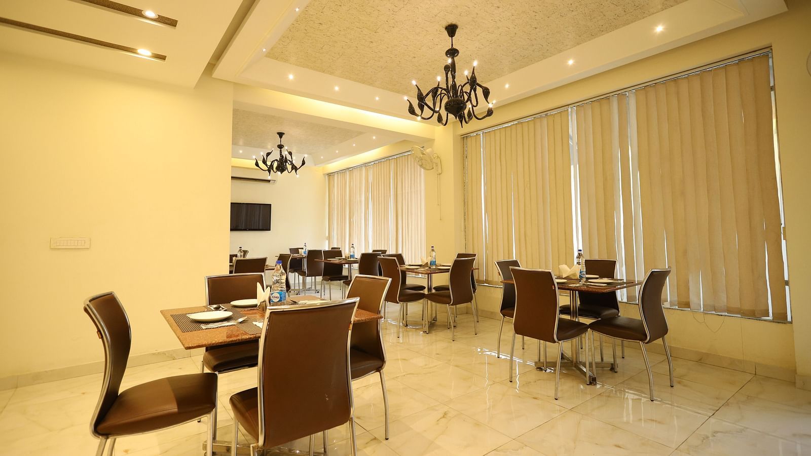A brightly lit dining area features multiple tables and chairs - Asian Suites Cyber Park, Gurgaon