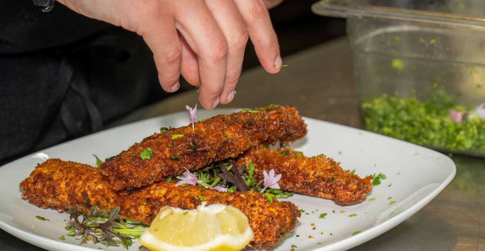 A chef plates golden-brown croquettes with lemon garnish and herbs at Narrow Gauge Inn.