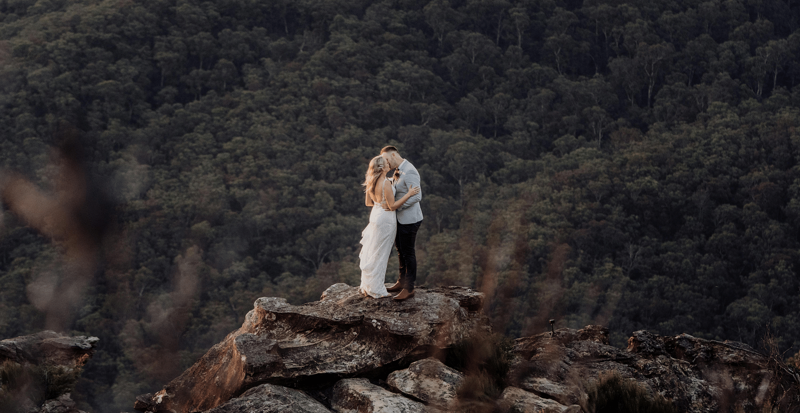 A bride and a groom posing for a photoshoot with a forest in the backdrop - The Groveland Hotel.