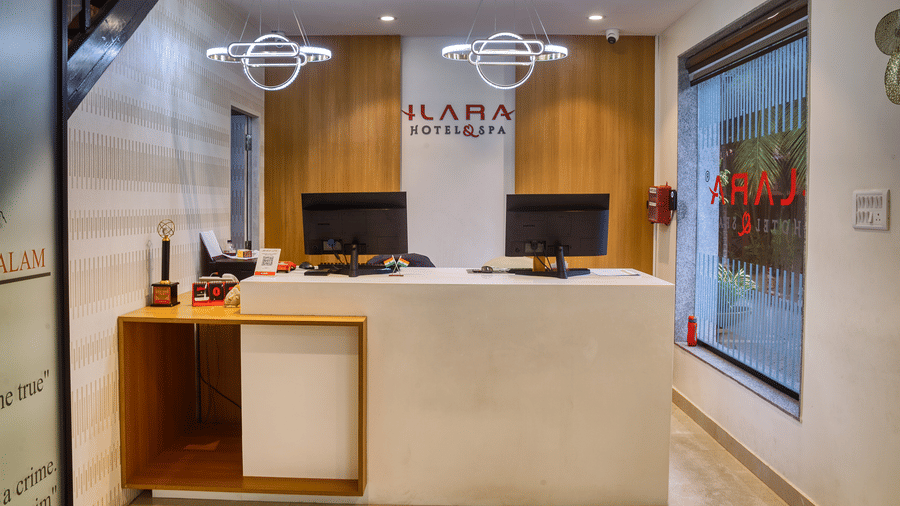 The well-lit and modern reception desk, featuring two computer monitors and clean wooden accents at Ilara Hotels & Spa, OMR, Chennai.