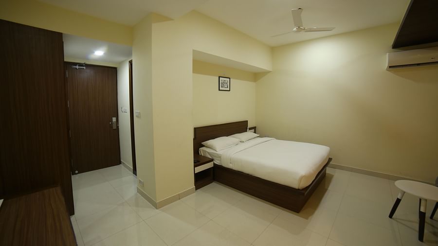 Mysore Gate Hotel, Bangalore Bengaluru A room featuring a well made bed an air-conditioner a table and a wardrobe - Mysore Gate Hotel Bangalore