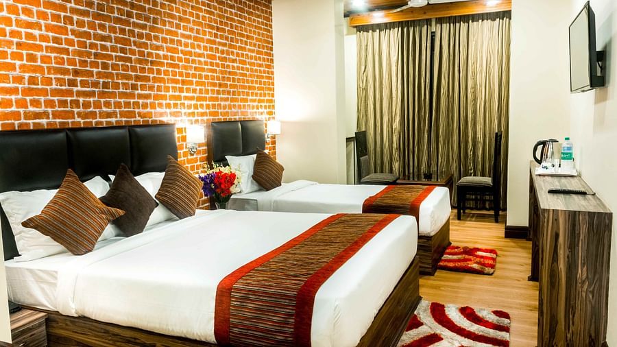 An image of a premium room with with twin beds, bed side tables, flat screen tv, chairs and tables, and other amenities - Ecotel Tin Tin, Bijanbari
