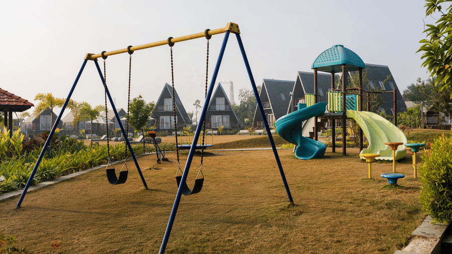 2 swings and a curved slide in an outdoor games area at Hotel Sonar Bangla, Taki.