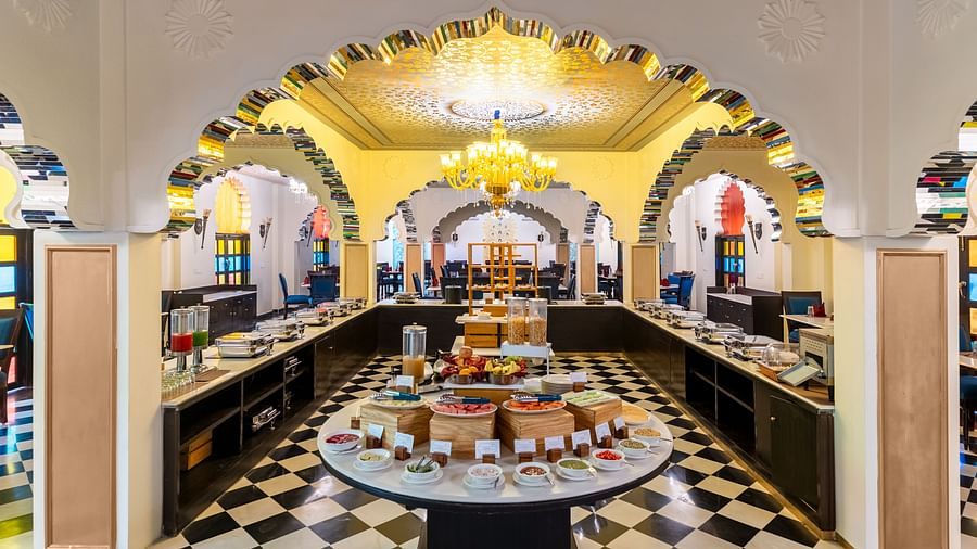 Lavish buffet dining area with black-and-white flooring and chandeliers at Kesar Bagh Palace.