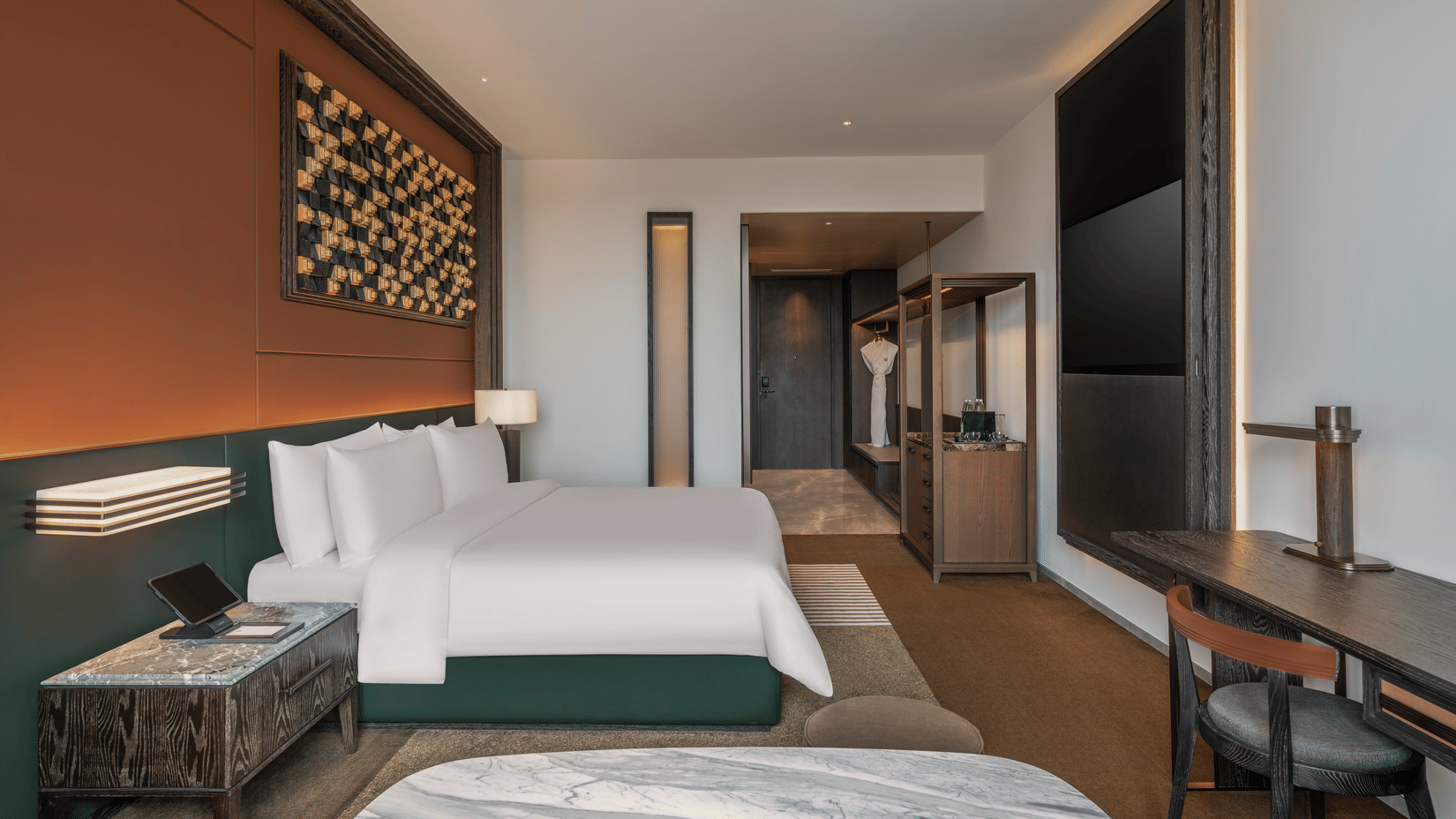 Side view of the Premium King room at The Residency Signature Madurai with a king bed, wall-mounted TV, wooden panelling, and warm ambient lighting.