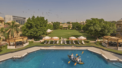 Guests enjoying kayaking in the swimming pool surrounded by sun loungers at Heritage Village Resorts & Spa, Manesar.