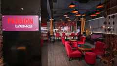 Interior of Passion Lounge at Park Plaza Ludhiana featuring red upholstered seating dark wooden flooring a glowing pink neon sign and warm ambient ceiling lighting.