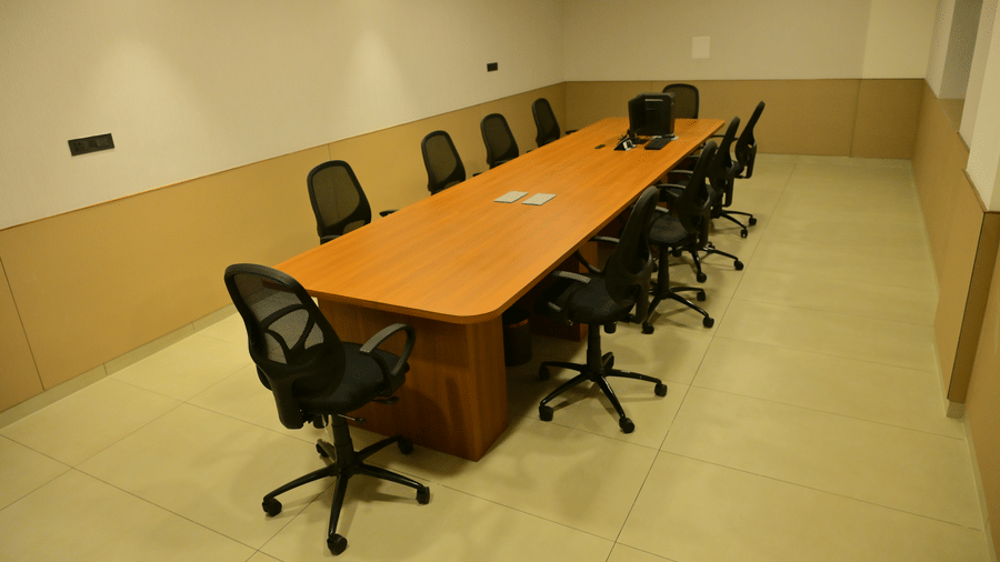 Boardroom at Bhavanis Vista By Icon Hosur with a long wooden conference table, black mesh chairs, and recessed ceiling lighting.