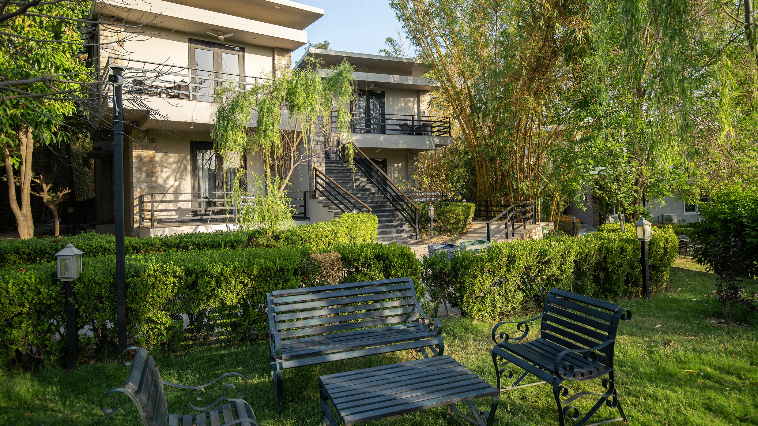 Lawn area of the resort building with a lush green garden and outdoor seating in the daytime at The Golden Tusk, Jim Corbett