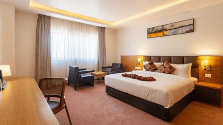 The spacious Presidential Suite featuring a neatly-made bed, seating area and work space at Mandala Norling Lords Prime Kathmandu.