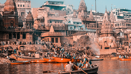 A bustling riverbank scene in Varanasi, India, with ghats and boats.