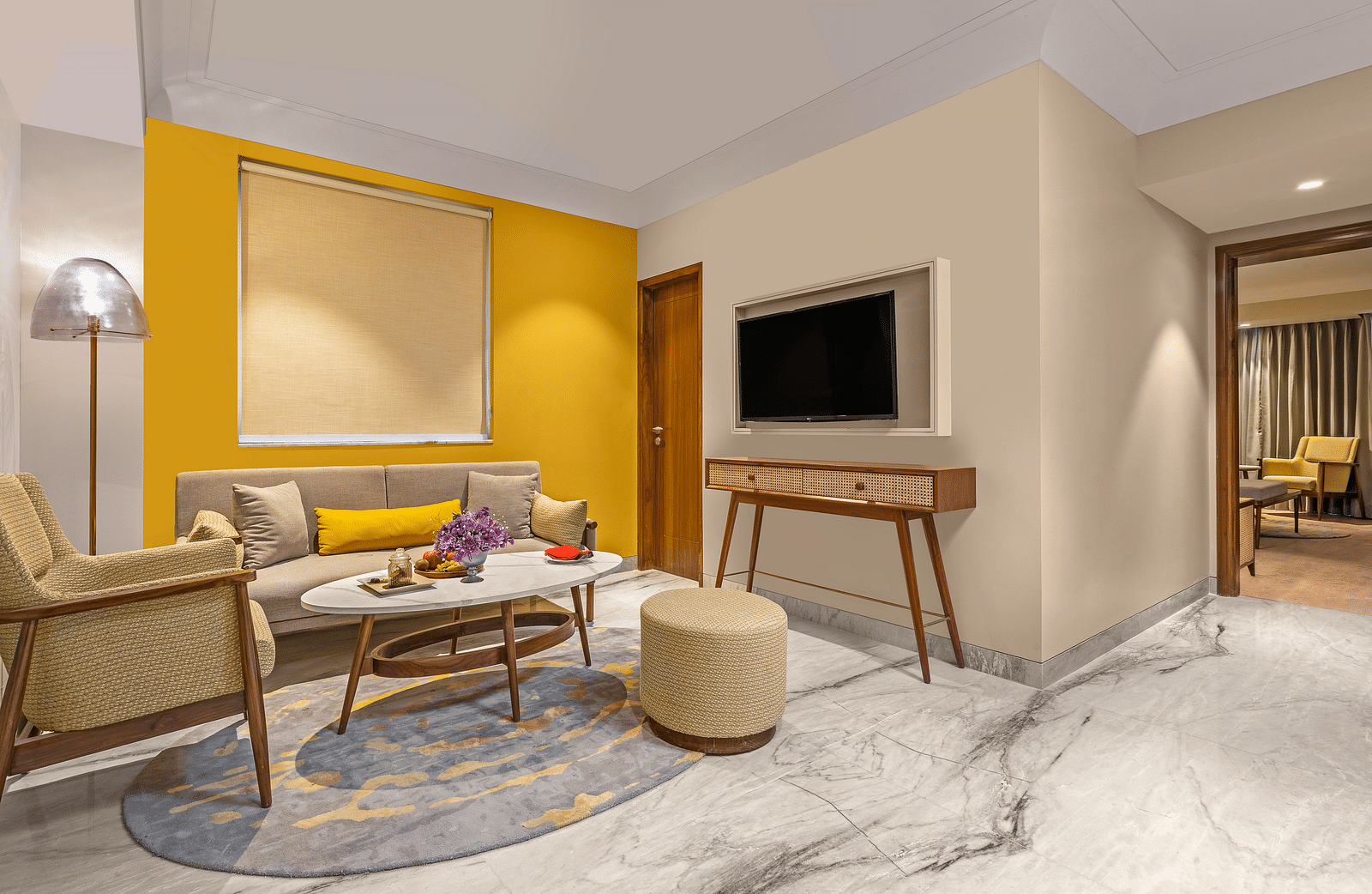 The room features a comfortable sofa with colourful pillows, a round coffee table, A floor lamp stands beside the sofa, providing ambient lighting.