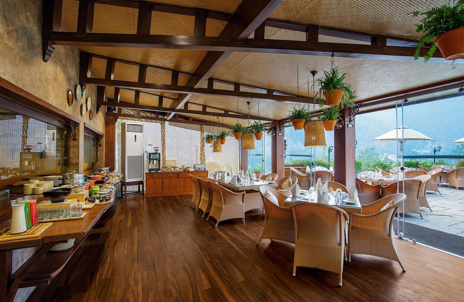A spacious restaurant with a wooden floor and exposed wooden beams on the ceiling. Large windows offer views of the outdoors.