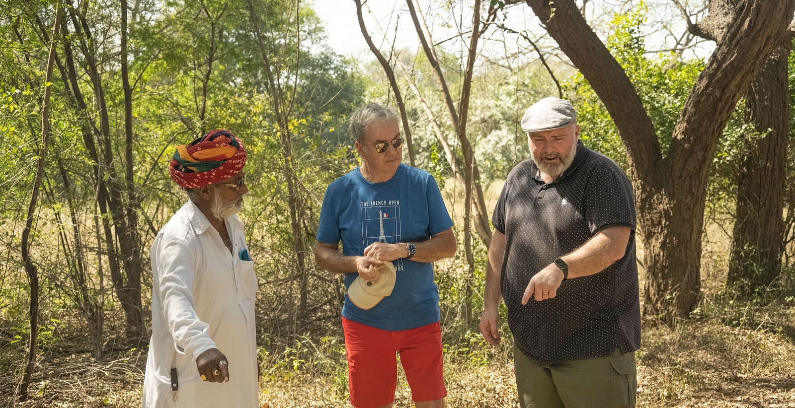 Three people having a conversation with trees behind them- Shahpura Bagh.