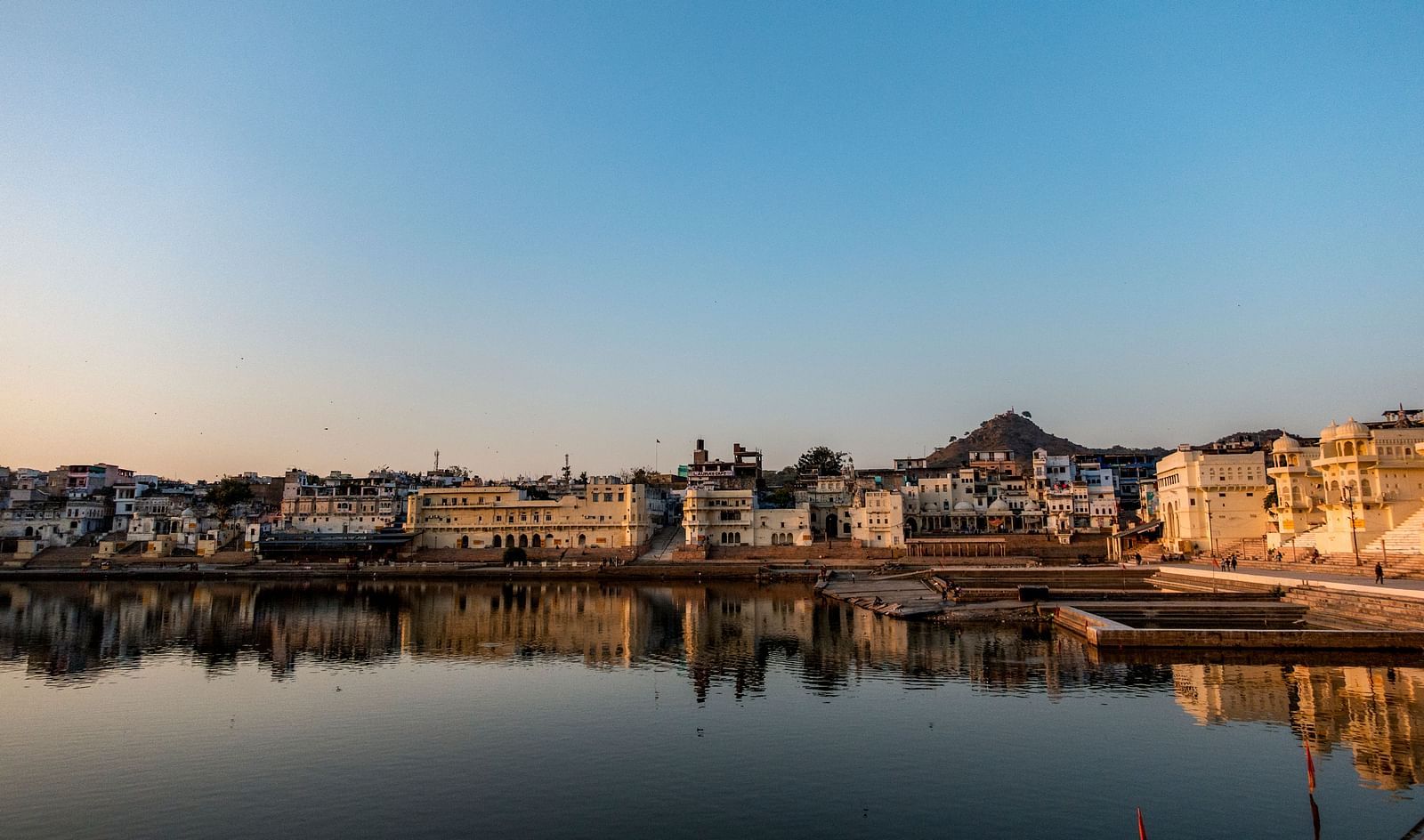 A serene view of a lake reflecting buildings at sunset or sunrise.