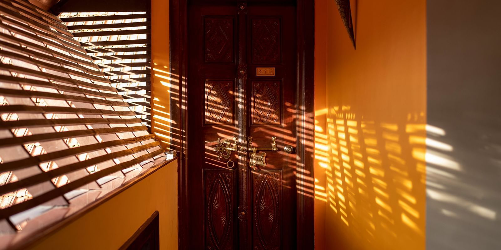 image of a wooden door with sunlight falling over it at hoysala village resort, hassan