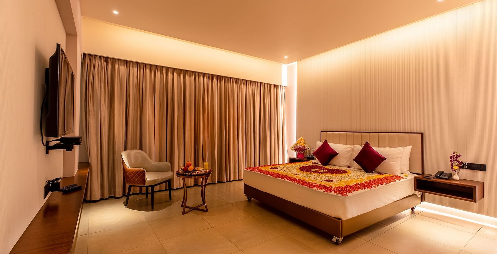 An image of a room featuring a bed adorned with flowers, with a television positioned in front at M Pro Palace.