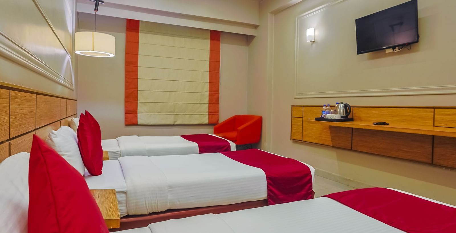 Room with red and white bedding, flat-screen TV at Max Hotel Prayagraj.