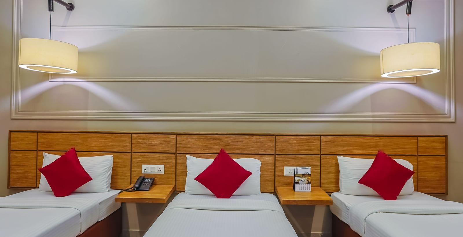 Neat room with three single beds and bright lighting at Max Hotel Prayagraj.