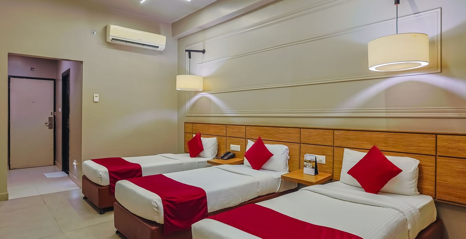 Clean and airy room with three single beds and minimalist decor at Max Hotel Prayagraj.