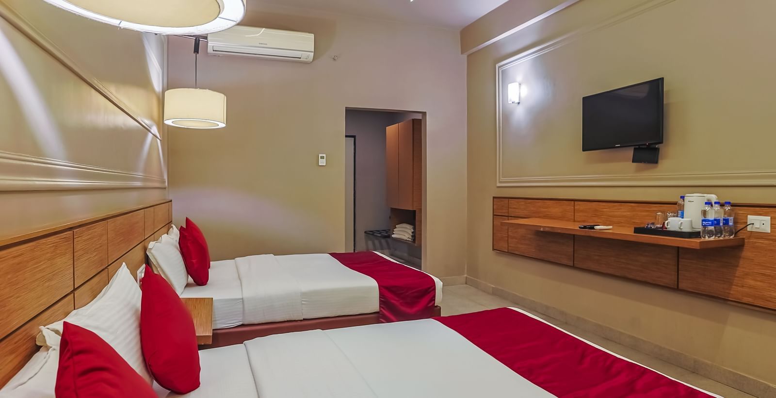 Room with red and white bedding and flat-screen TV at Max Hotel Prayagraj.