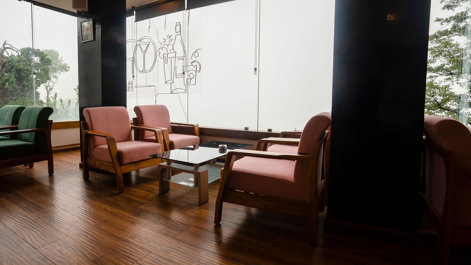 A wide shot of a seating area at Orsino Spa Resort with large windows and several armchairs with light-coloured upholstery and small tables on a polished wooden floor.