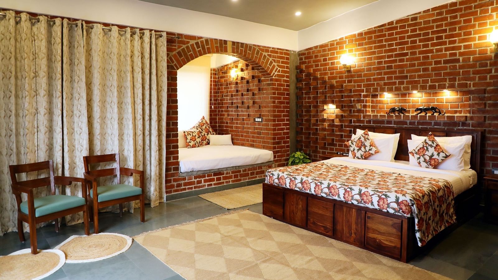 A bedroom at Tisya Farms, Gurgaon with a double bed, chairs, brick walls, curtains, and overhead lighting.