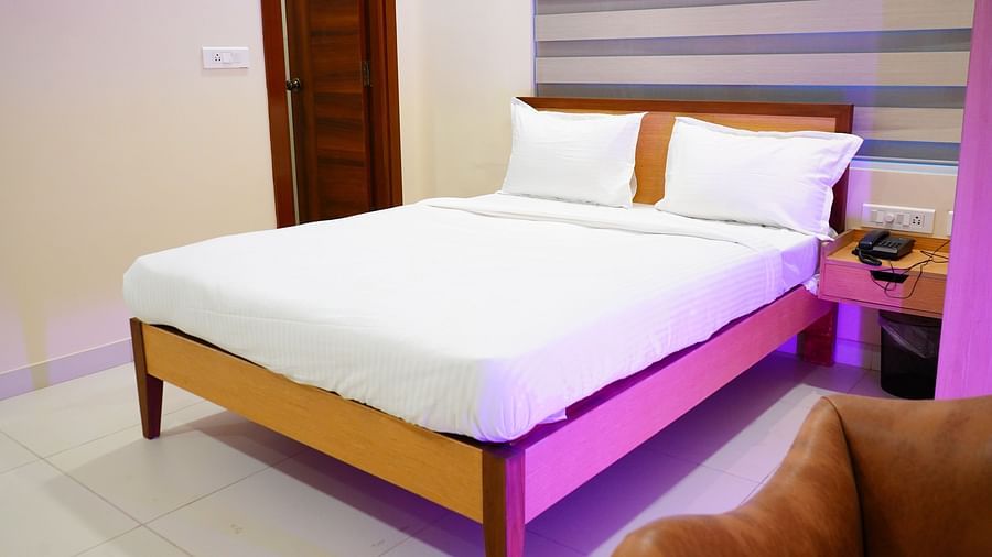 A room featuring a tidy bed, a side drawer, a sofa and a dialling phone - A M Suites