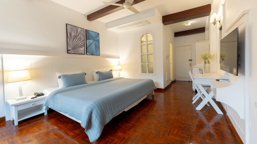 A full view of a deluxe suite showing the bed, seating area, work desk, and wall-mounted television - Johnson Lodge & Spa, Manali