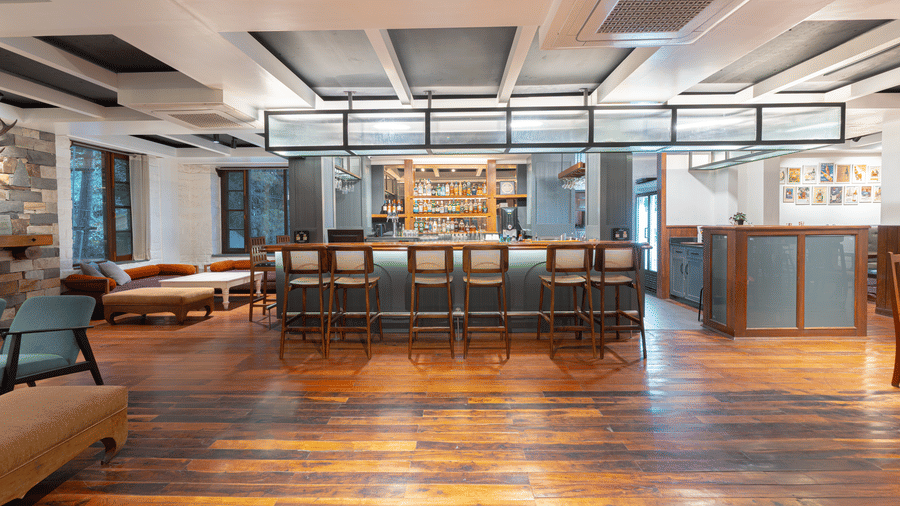 A perspective shot of the main bar hall showcasing the symmetry of the ceiling design and rich wood textures - Johnson Lodge & Spa, Manali