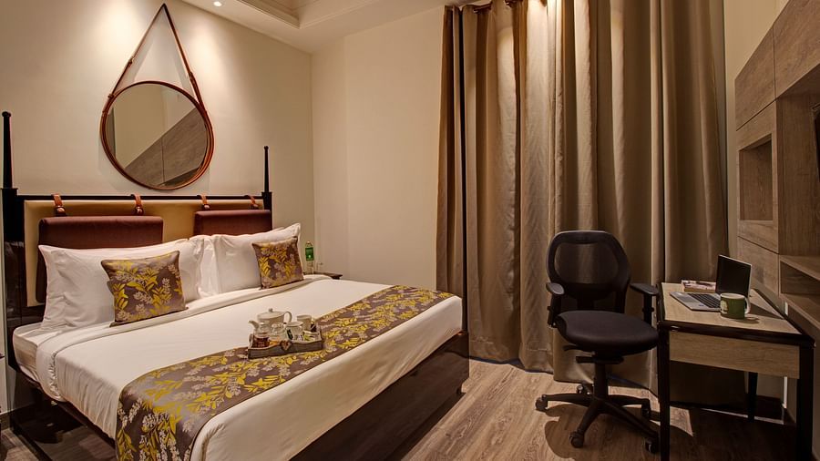 a king bed with a study table opposite the bed inside the Two bedroom Executive Suite - Rhythm Gurugram