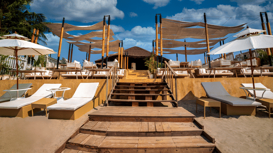 front view of the entrance of the saz on the beach restaurant featuring white coloured sun loungers at the entrance