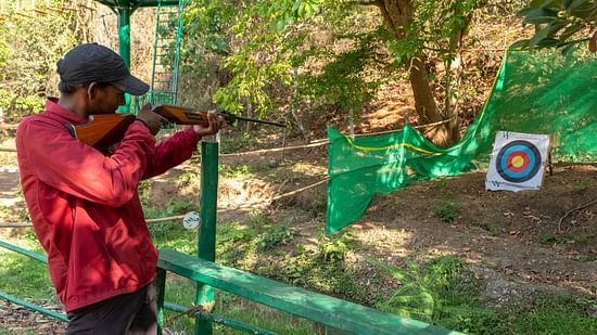 Man aiming at a target in an outdoor shooting range activity. | Stone Wood Jungle Resort, Dandeli