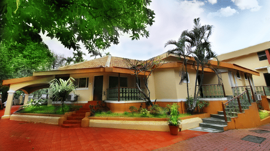 An overview of the exterior facade of the Zara's Resort, Khandala, surrounded by greenery and blue sky in the background.