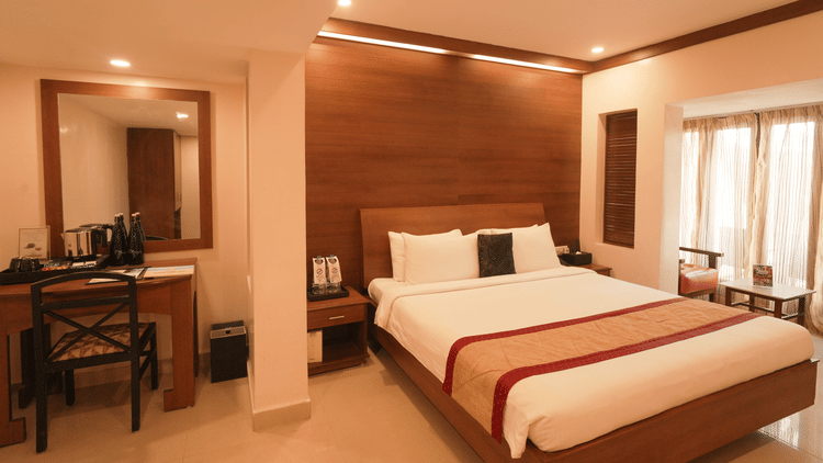 A room with a neatly arranged bed with good lighting and a desk and chair arranged in the side.