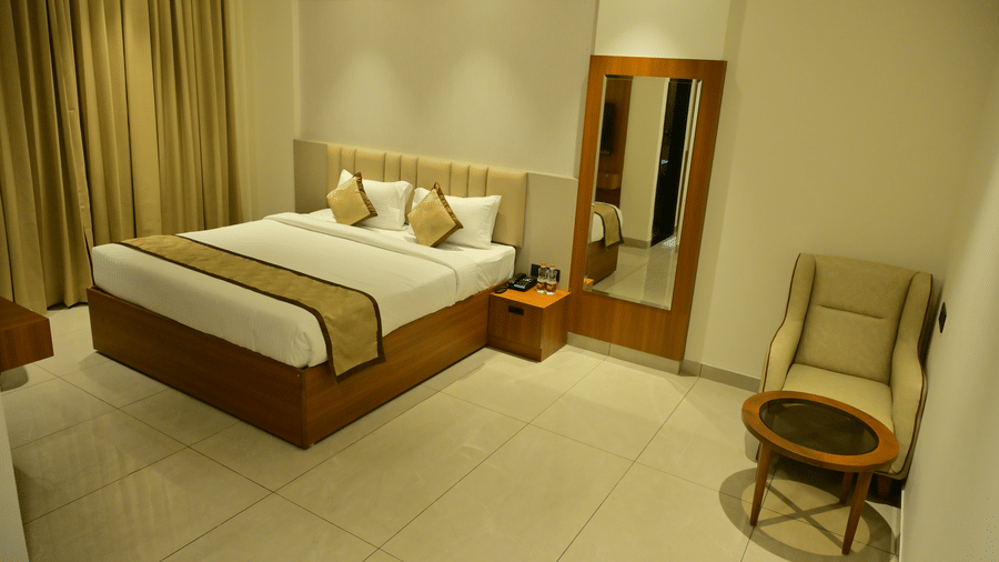 Bedroom of Bhavanis Vista By Icon featuring a bed, a headboard, an armchair, and a mirror.