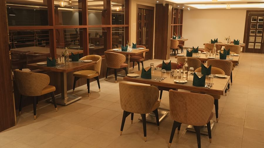 An image of a restaurant with several chairs and dining tables at Mastiff Grand, Dharwad