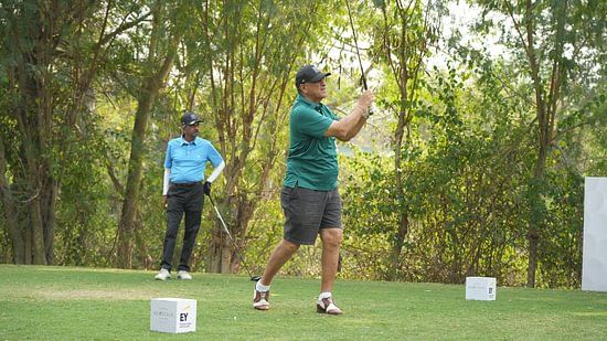 Golfer taking a powerful swing during a professional golf match surrounded by greenery.