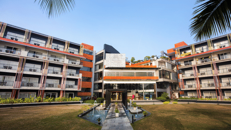 Front exterior of Hotel Sonar Bangla, Taki, featuring vibrant architecture, a fountain, and lush garden pathways under a clear sky.
