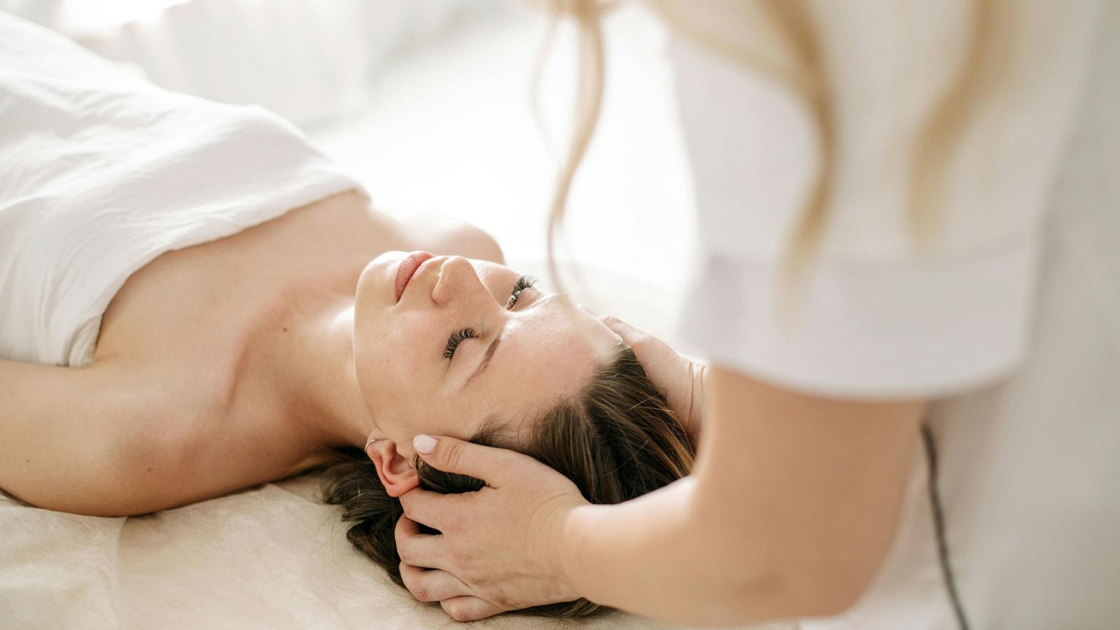 A therapist performing a soothing head massage on a client to promote relaxation.