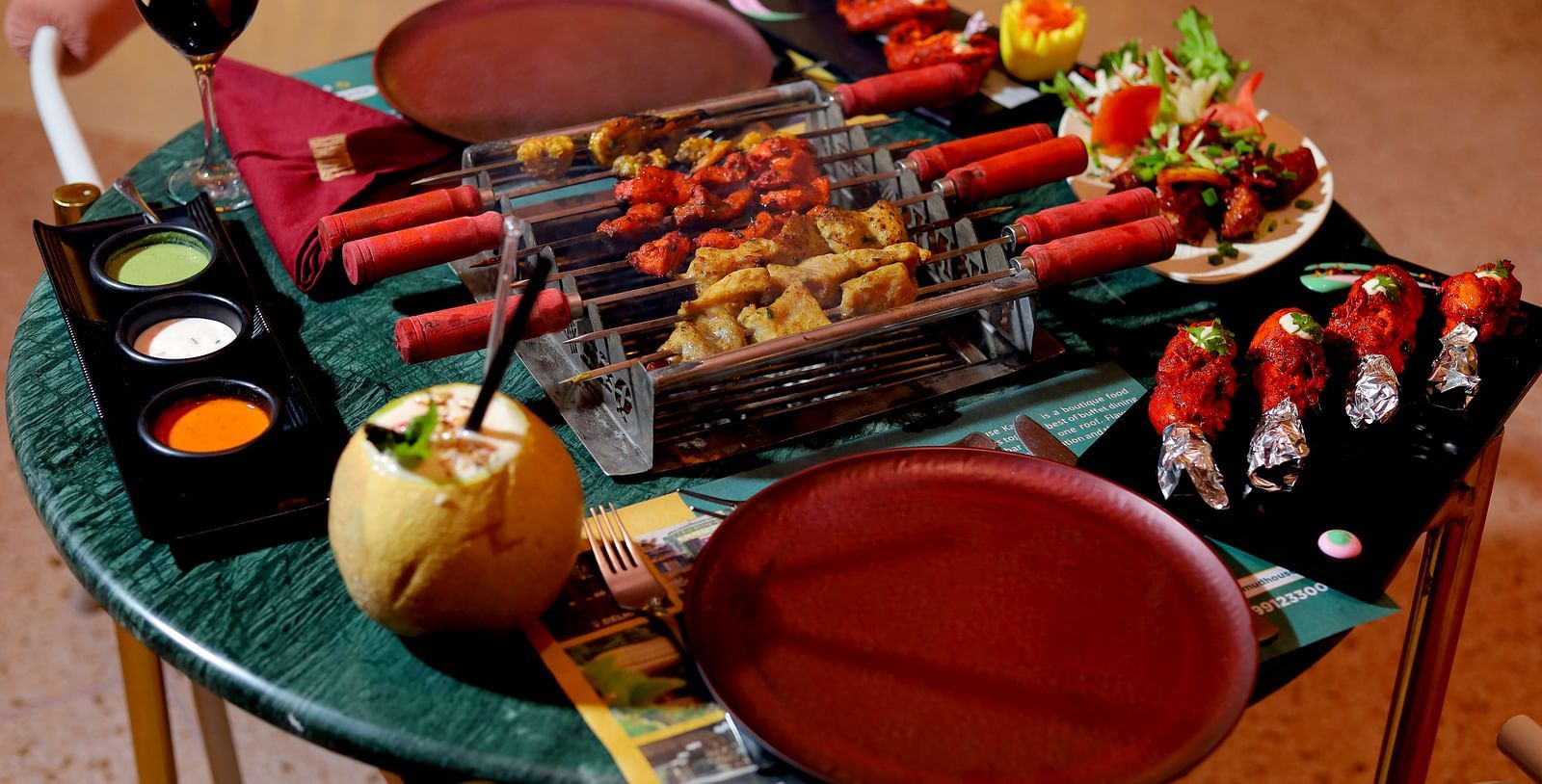 An image of a barbecue table where several eatables are placed like grilled meat, spices, condiments, sauces, dishes, etc at Themis Barbecue House, Ambala